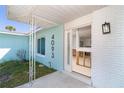Covered porch leading into a house with aqua colored siding and white trim. Interior is in need of repair at 4093 Pelican Shores Cir, Englewood, FL 34223