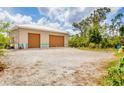 Spacious detached two-car garage with ample parking space in the gravel driveway surrounded by trees at 5250 Callaway St, Port Charlotte, FL 33981