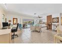 Open-concept living space with tile flooring, a desk area, and sliding glass doors leading to a screened-in pool area at 5879 Venisota Rd, Venice, FL 34293