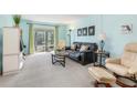 Bright living room with a black sofa, comfy chairs, sliding doors to a balcony, and neutral-colored carpet at 708 Tamiami S Trl # 216, Venice, FL 34285