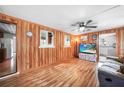 Cozy living room featuring a ceiling fan, wood-paneled walls, and hardwood floors at 857 Palmetto St, Englewood, FL 34223