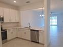 Bright kitchen featuring white cabinets, stainless steel appliances, and views of the dining and living area at 8661 Seasalt Loop, Englewood, FL 34224