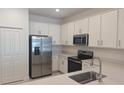 Modern kitchen featuring stainless steel appliances, white cabinets, stone countertops, and a pantry at 8661 Seasalt Loop, Englewood, FL 34224
