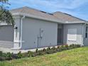 Modern home exterior featuring neutral siding, manicured flower beds, and a small covered entryway at 8673 Seasalt Loop, Englewood, FL 34224
