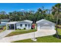 An updated white home with a long driveway, covered car port and two-car garage on a lush lawn at 868 Harvard St, Englewood, FL 34223