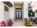 Covered front entry with double glass doors and stone accents, complimented by vibrant plants at 9470 Wacker Ter, Port Charlotte, FL 33981