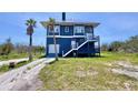 Beautiful coastal home boasting blue siding, a garage, an elevated deck, and complemented by tropical palm trees at 9594 Doubloon Trl, Placida, FL 33946