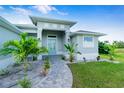 Beautifully landscaped home featuring a welcoming front entrance with a patterned walkway and decorative blue door at 13344 Gershwin Ln, Port Charlotte, FL 33981