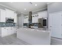 Modern kitchen featuring white cabinetry, stainless steel appliances, and a center island with a marble countertop at 13344 Gershwin Ln, Port Charlotte, FL 33981