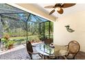 A screened lanai with seating area and brick flooring with a view of a wooded area at 13392 Abercrombie Dr, Englewood, FL 34223