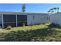 Exterior view of a home's back side, featuring a screened-in porch area and a storage shed in the yard at 13561 Darnell Ave, Port Charlotte, FL 33981
