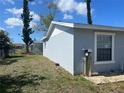 Rear view of a single-story home, showing the utility access point on the side of the house and partial fence at 13561 Darnell Ave, Port Charlotte, FL 33981