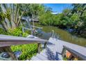 Wooden dock and canal with boat lift surrounded by green foliage and clear water access at 142 Sunaire Ter, Nokomis, FL 34275
