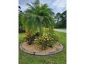 Lush landscaping featuring a mature palm tree and colorful plants within a circular rock garden at 142 Yellow Pine Dr, Rotonda West, FL 33947
