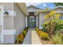 Close-up of the inviting front entrance, framed by colorful bushes and a gray facade at 143 Crevalle Rd, Rotonda West, FL 33947
