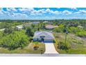 Aerial view of a single-story home featuring a well-manicured lawn and an attached garage in a lush community at 149 Garland Way, Rotonda West, FL 33947