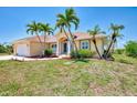 Desirable home showing lush lawn, red rock landscape, and mature palm trees in the front yard at 15020 Acorn Cir, Port Charlotte, FL 33981