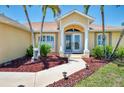 Inviting front entryway showcasing double doors, manicured landscaping, and stylish outdoor lighting at 15020 Acorn Cir, Port Charlotte, FL 33981