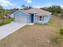 Inviting single-story home boasts a spacious driveway, light blue exterior paint and manicured lawn at 1664 Karluk St, North Port, FL 34287