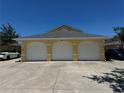 Attached three-car garage with white doors and a wide concrete driveway at 169 Boundary Blvd # 169P, Rotonda West, FL 33947