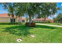 A lush green lawn and mature trees in front of a well-maintained home with a tiled roof at 2692 Wax Myrtle Ct, Port Charlotte, FL 33953