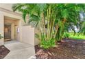Inviting home entrance with a glass front door, tropical landscaping, and a view of the nearby water at 4612 Club Dr # D102, Port Charlotte, FL 33953
