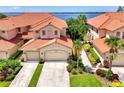 Beautiful two-story villa with a terra cotta roof, multi-car garage, lush tropical landscaping, and waterfront views at 4612 Club Dr # D102, Port Charlotte, FL 33953