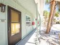 Exterior view of building featuring a brown door, light green siding, and a concrete pathway leading to individual units at 5041 N Beach Rd # 2A And 2B, Englewood, FL 34223