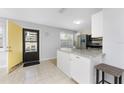 Bright kitchen featuring white cabinetry, granite countertops, stainless steel appliances, and yellow-painted front door at 5041 N Beach Rd # 2A And 2B, Englewood, FL 34223
