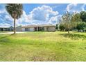 The well-maintained ranch-style home has a three-car garage, lush green lawn, and sunny skies at 6206 Marcum St, Englewood, FL 34224