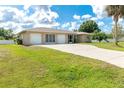 Low angle of the well-maintained ranch-style home with three-car garage and a grassy lot at 6206 Marcum St, Englewood, FL 34224