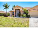 Welcoming single-story home featuring a well-manicured lawn, mature palms, covered entry, and attached two-car garage at 6461 Thorman Rd, Port Charlotte, FL 33981