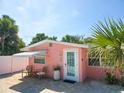 Charming beach cottage with a delightful pink exterior, brick patio, seating, and well-manicured landscaping at 95 Coquina Ln, Englewood, FL 34223