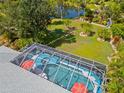 Aerial view of a screened-in pool, landscaped backyard with garden, and serene pond at 116 Tournament Rd, Rotonda West, FL 33947