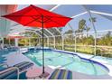 Inviting screened-in pool area with ample seating, an umbrella, and a view of the lush backyard at 116 Tournament Rd, Rotonda West, FL 33947