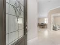 Inviting home foyer with a decorative glass door, tiled floors, and a view into the open dining and living areas at 13859 Vadini St, Venice, FL 34293