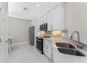 Modern kitchen showcasing stainless steel appliances, white cabinets, and a stylish backsplash with bright natural light at 13859 Vadini St, Venice, FL 34293