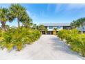 Coastal home surrounded by lush landscaping with a sandy driveway leading up to the residence at 180 N Gulf Blvd # 5, Placida, FL 33946