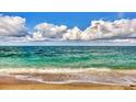 Gentle ocean waves rolling onto a sandy beach under a bright blue sky with fluffy white clouds at 2700 N Beach Rd # B205, Englewood, FL 34223