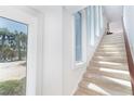 Bright staircase featuring carpeted stairs, white walls, and a view of palm trees at 6430 Manasota Key Rd, Englewood, FL 34223