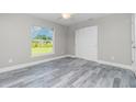 This bedroom features modern gray floors, white trim, a ceiling fan, a window and closet with doors at 8270 Cook Ct, Port Charlotte, FL 33981