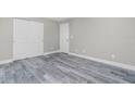 An airy bedroom showcases modern gray wood-look floors, white trim and closet with white doors at 8270 Cook Ct, Port Charlotte, FL 33981