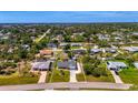Expansive aerial view showcasing a single-story home nestled in a lush, green neighborhood with mature trees and landscaping at 9869 Gulfstream Blvd, Englewood, FL 34224