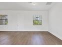 Bright living room with tile floors, fresh white paint, and two large windows overlooking landscaping at 10242 Hallendale Dr, Port Charlotte, FL 33981