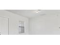 A bright room has a door on the left and a single window with blinds at 10242 Hallendale Dr, Port Charlotte, FL 33981