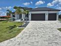A long driveway leading up to a three-car garage with palm trees and a landscaped yard at 10454 Atenia St, Port Charlotte, FL 33981