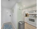 Galley kitchen with white appliances, light countertops, and a stainless steel trash receptacle at 1501 Beach Rd # 310, Englewood, FL 34223