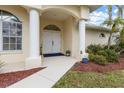 Inviting home entryway with double doors, pillars, arched window, and lush landscaping at 2295 Chilcote Ter, Port Charlotte, FL 33981