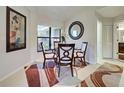 Cozy dining area with a glass table, four chairs, and a decorative mirror, next to a window and doorway at 232 Southampton Ln # 259, Venice, FL 34293