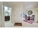 Bright foyer with tiled floors, a view of a bathroom, and a dining area with a glass table and four chairs at 232 Southampton Ln # 259, Venice, FL 34293